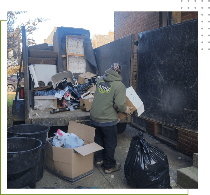 A man in green jacket standing next to trash.