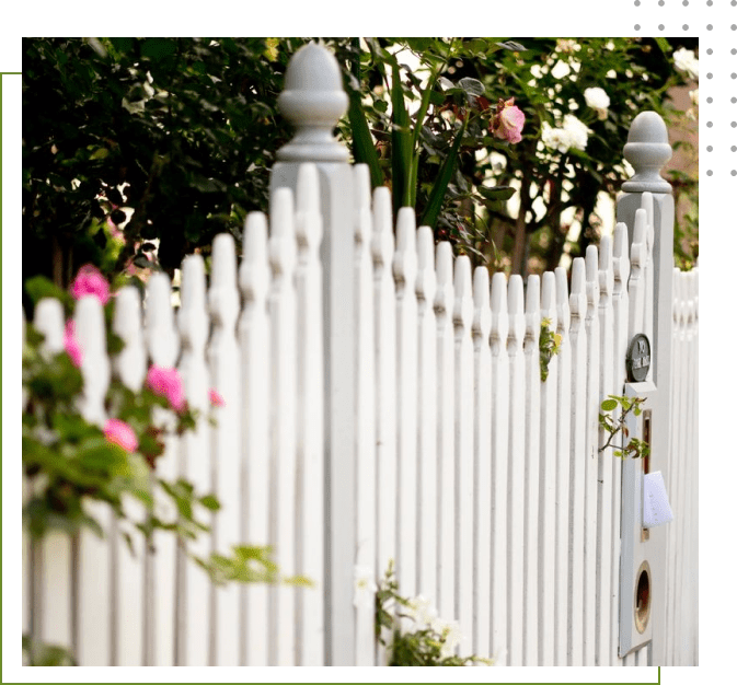 A white fence with flowers growing on it.