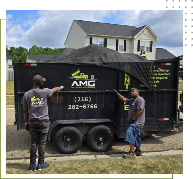 Two men standing next to a dumpster.