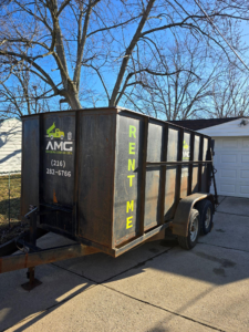 AMG Junk Removal truck parked beside a backyard shed for hauling and disposal