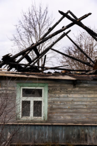 Old broken backyard shed needing removal due to weather damage and clutter