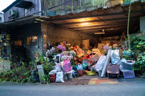 A cluttered garage overflowing with boxes, bags, and miscellaneous items