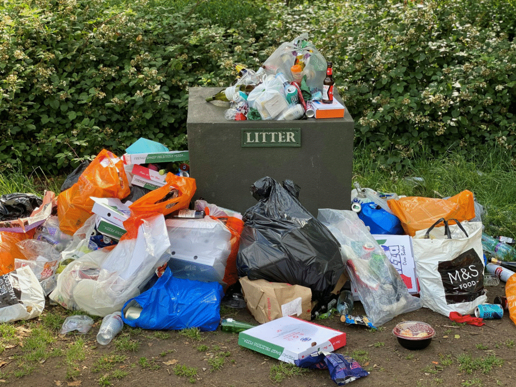 Trash bags and litter spilling from a bin.