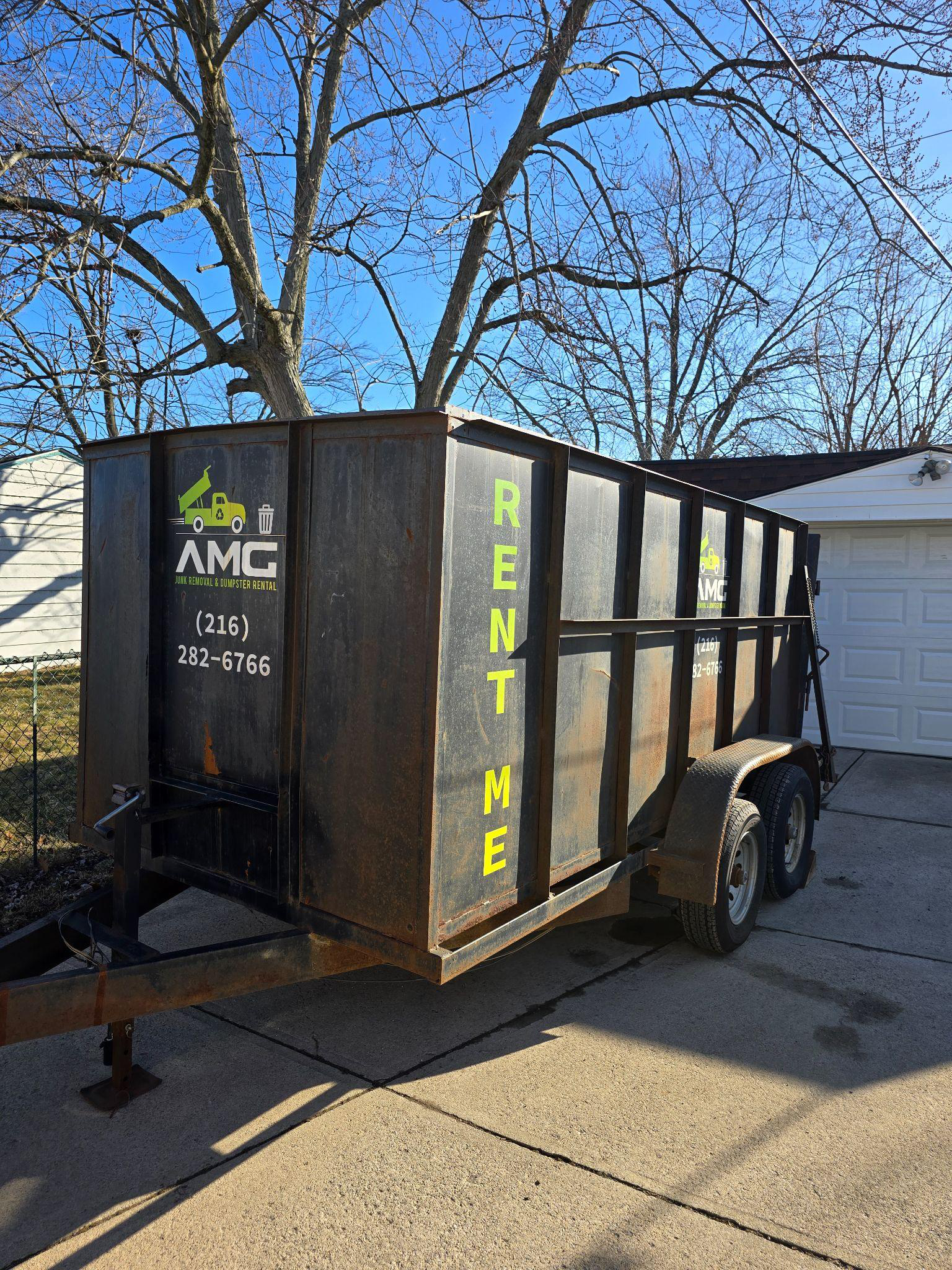 A large dumpster rental placed in a residential driveway, filled with renovation and household debris