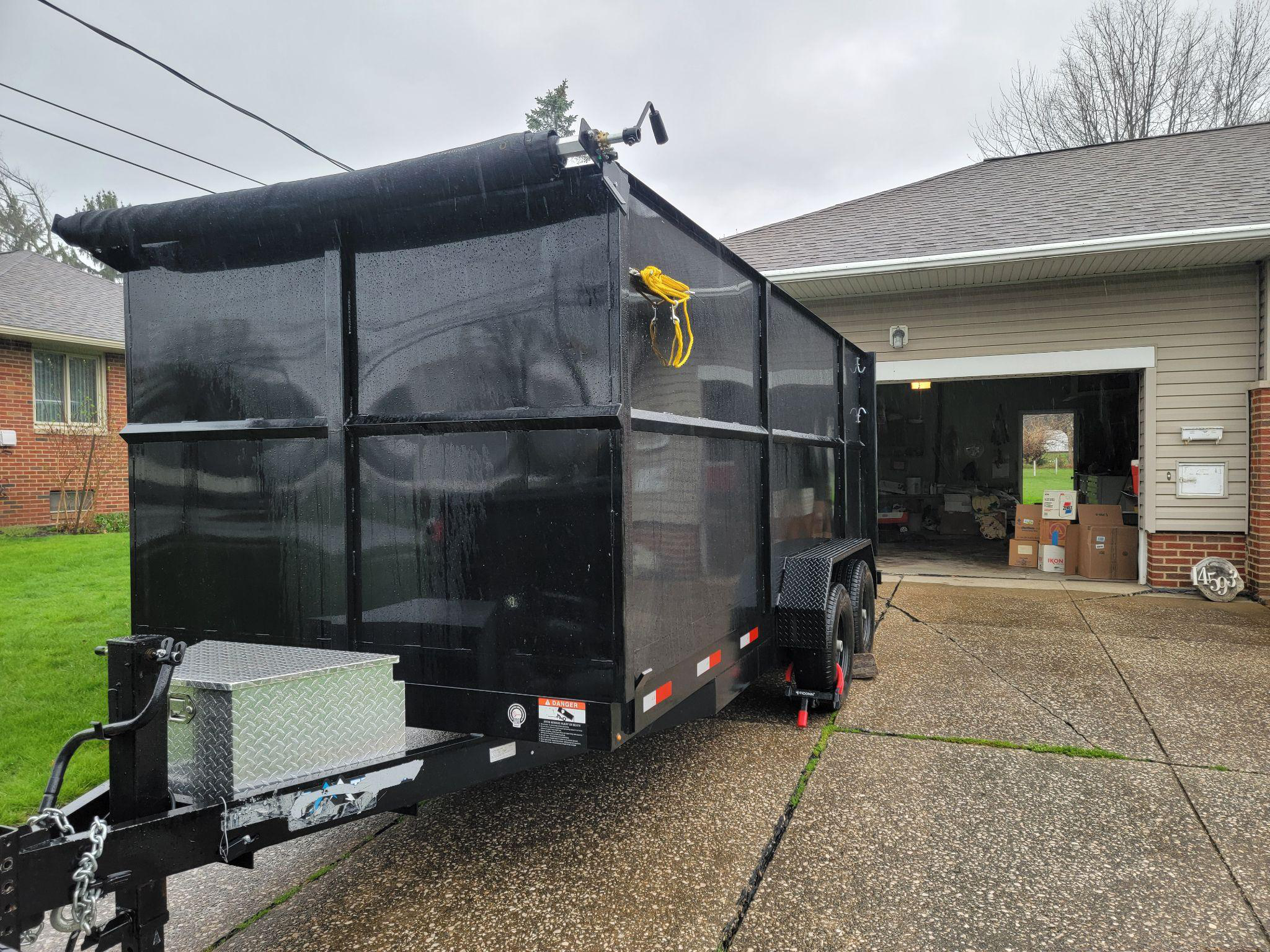 A dumpster outside an open garage.