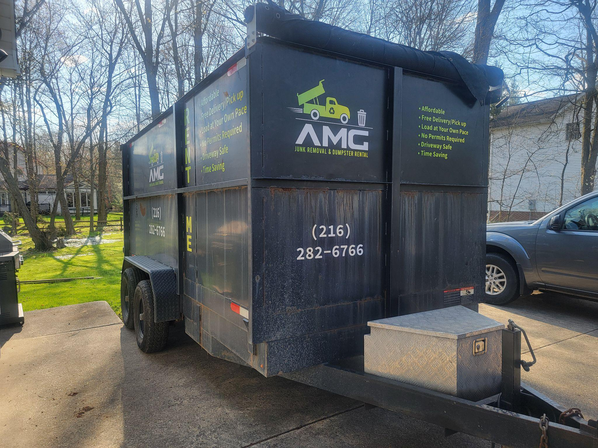 A dumpster with trees in the background.
