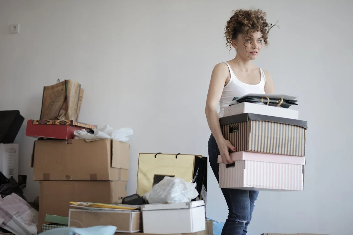 A person carrying a stack of cardboard boxes.