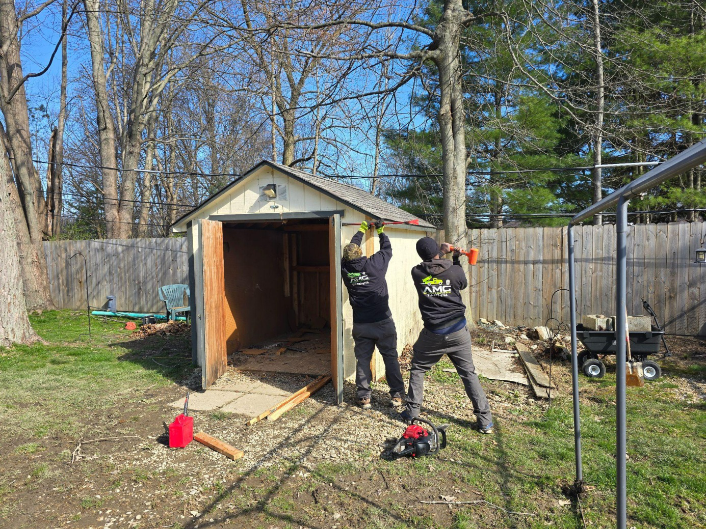 Two people taking down a shed.