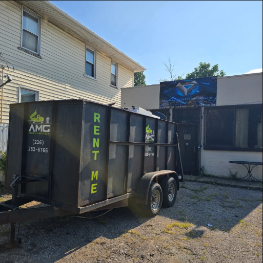 Large dumpster placed in a residential driveway for hauling away junk and debris.