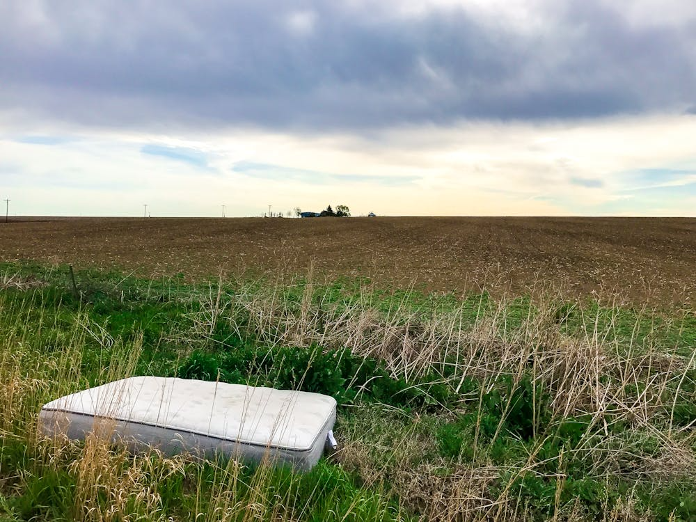 Abandoned mattress left in a field showing the risks of illegal mattress disposal in Solon.