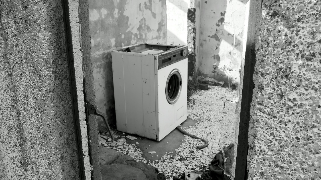 Old washing machine sitting unused in a basement, ready for professional appliance removal in Cleveland.