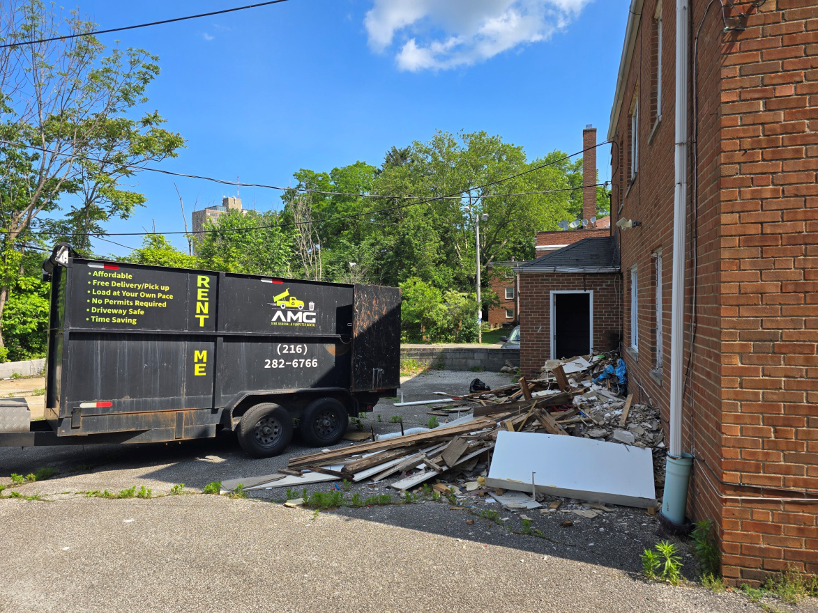 AMG commercial junk removal in Cleveland – black dumpster parked near a local business.
